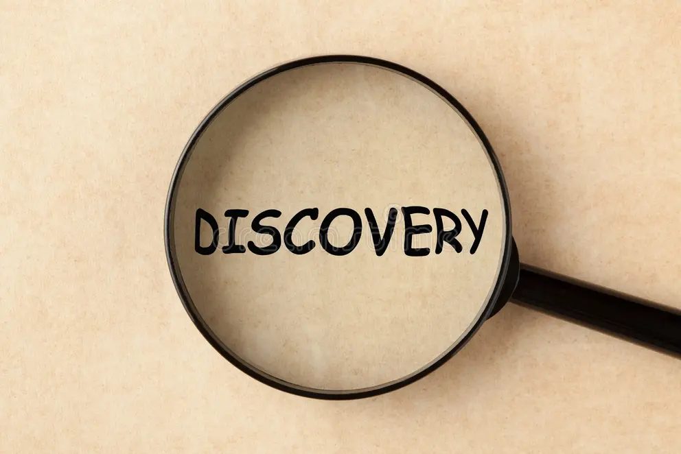 A magnifying glass over the word DISCOVERY on a tan paper background